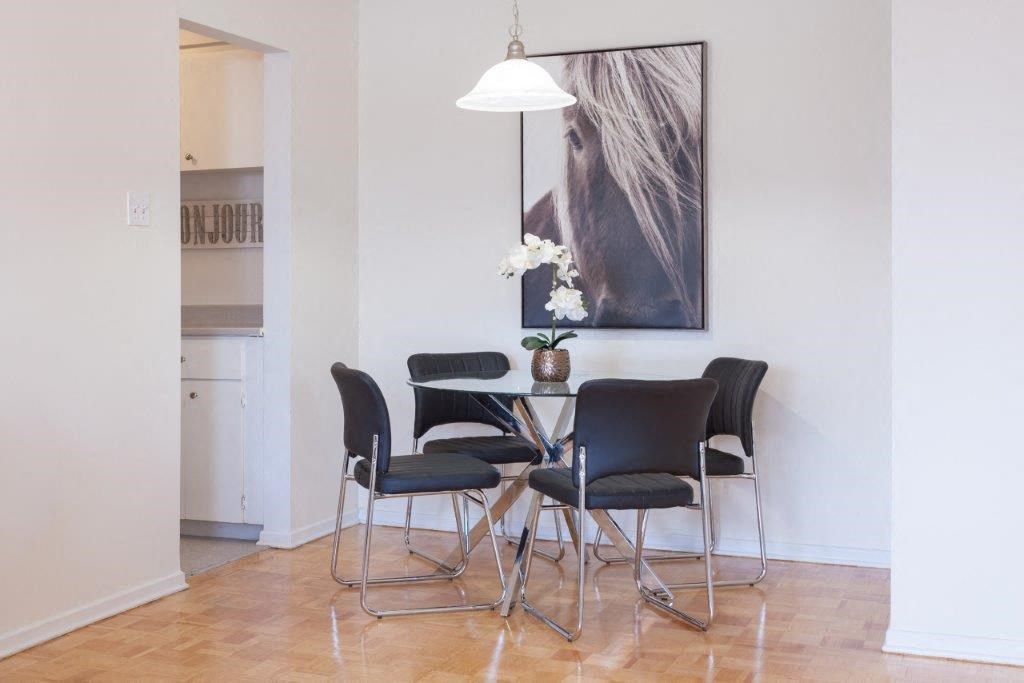 a dining room with a table and chairs and a painting on the wall