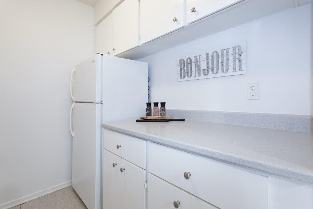 a kitchen with white cabinets and a refrigerator