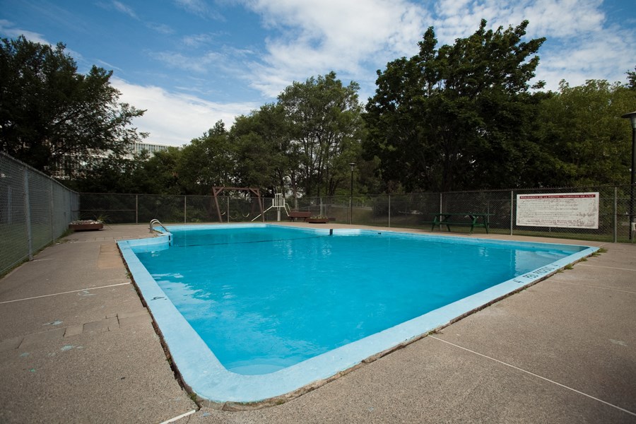 a swimming pool in a fenced in area with trees in the background