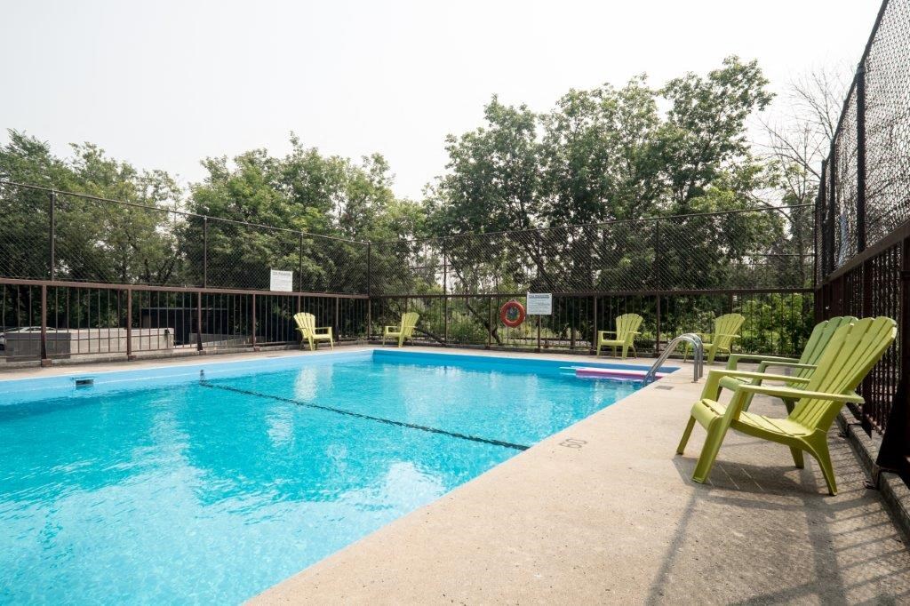 a swimming pool with green chairs and a fence around it