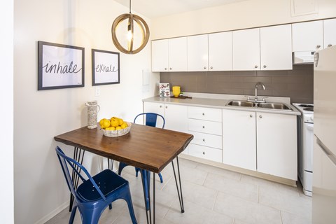 A kitchen with a table and chairs and a fridge.