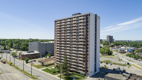 A tall building with many windows is surrounded by a parking lot.