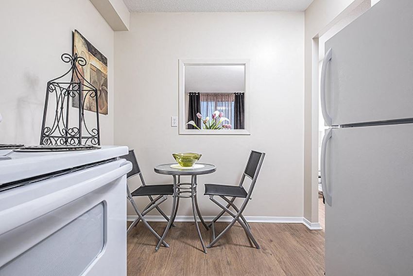 a small table and chairs in a kitchen next to a stove and refrigerator