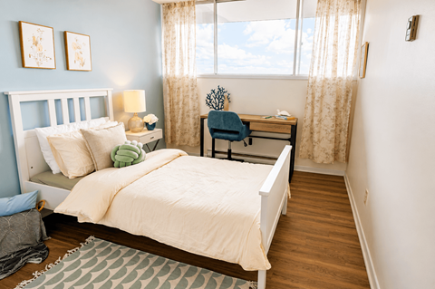 A bedroom with a bed, desk, and chair.