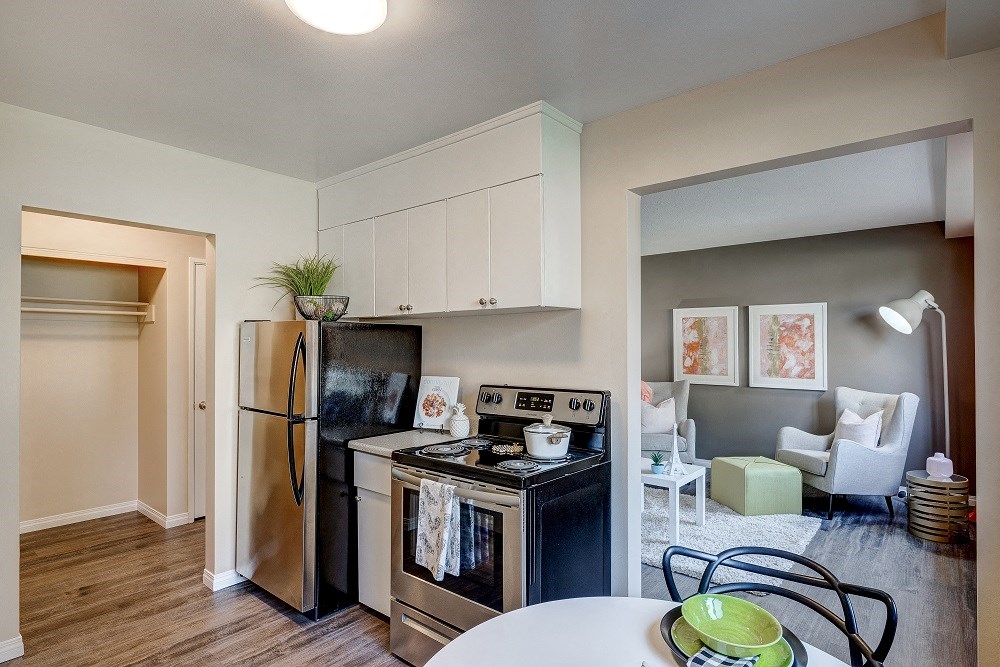 an open kitchen and living room with stainless steel appliances and a table