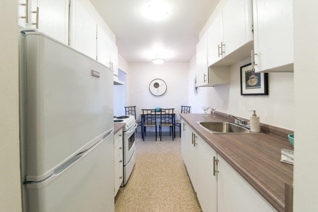 a kitchen with white cabinets and a sink and a refrigerator