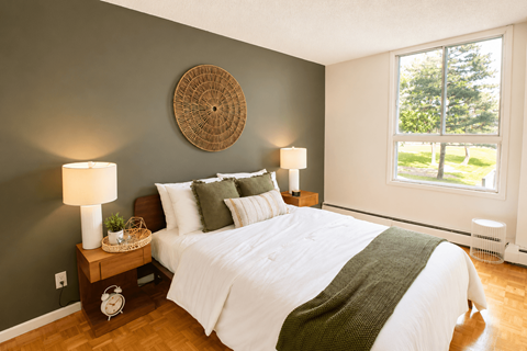 A bedroom with a white bed and a green blanket.