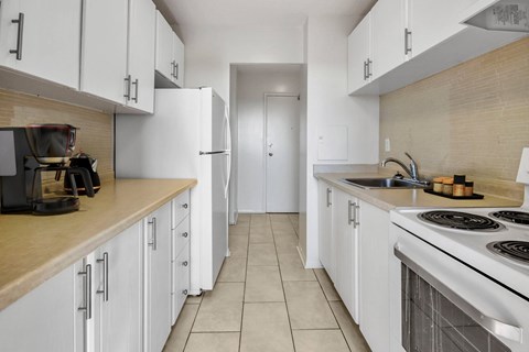 A kitchen with white cabinets and a stove top oven.