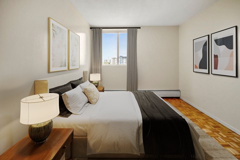 A bedroom with a large bed and a window overlooking the city.