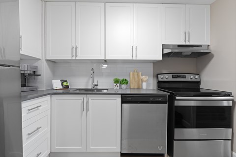A modern kitchen with white cabinets and stainless steel appliances.