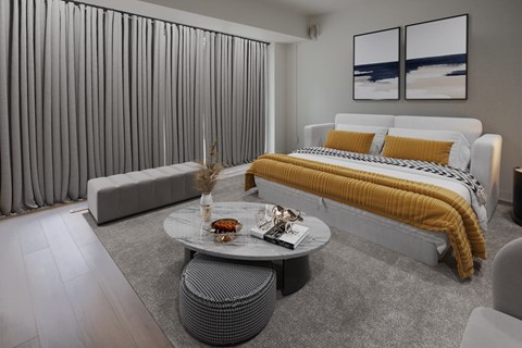 A modern bedroom with a large bed and a grey sofa.
