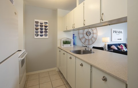 A kitchen with white cabinets and a Prada sign on the wall.