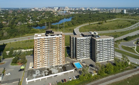 Two large buildings are situated next to a pool and a road.