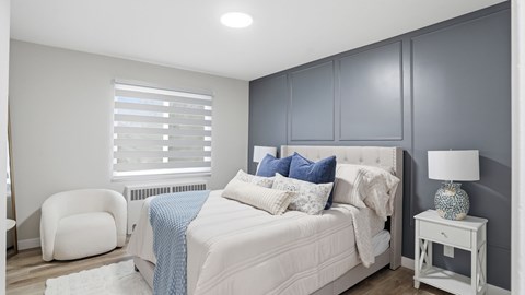 A bedroom with a white bed and a white chair.
