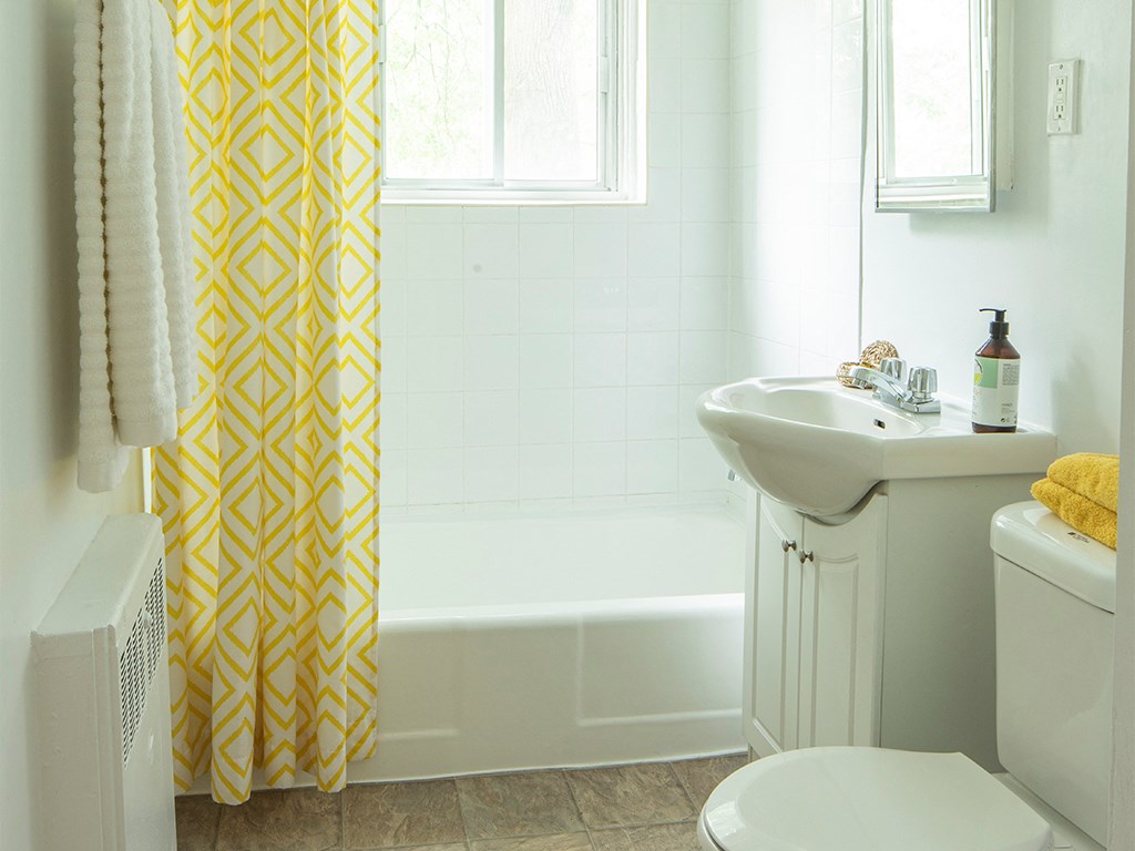 a white bathroom with a yellow and white shower curtain