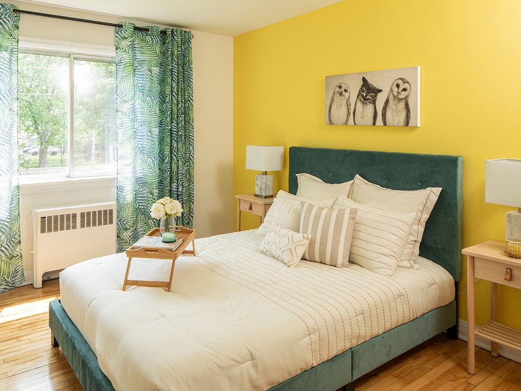 a bedroom with a bed and a yellow wall and a window
