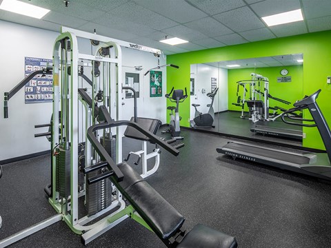 a gym with weights and other equipment in a building with green walls
