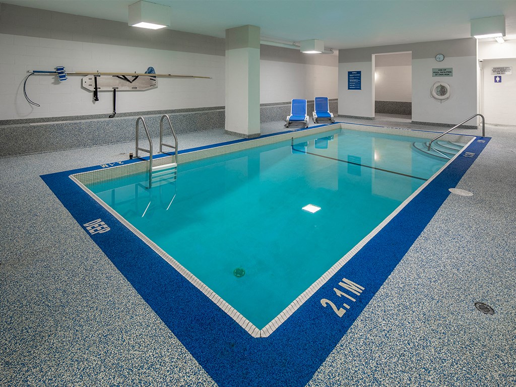 a large indoor pool with blue chairs and a blue rug