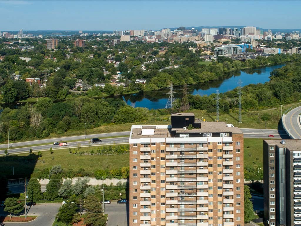 an aerial view of an apartment building with a river and a city in the background