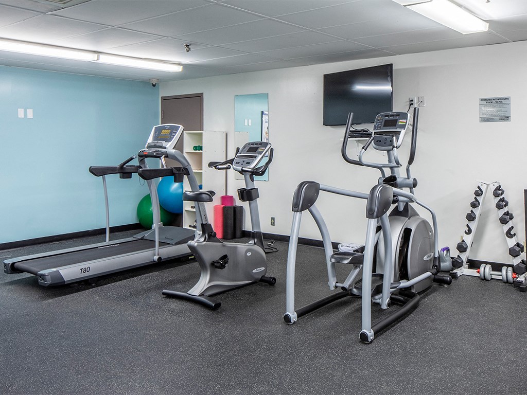 a gym with exercise equipment and a tv
