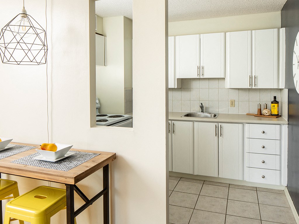 a kitchen with white cabinets and a table and yellow stools