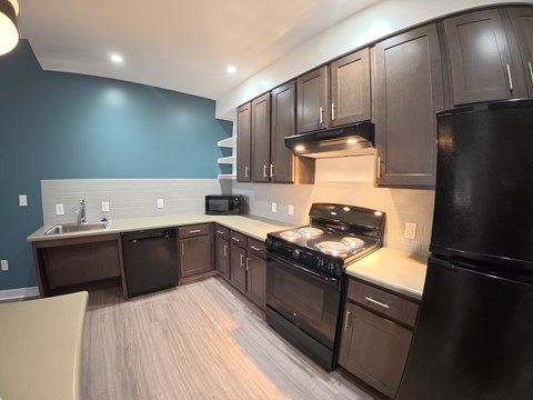 A kitchen with black appliances and brown cabinets.