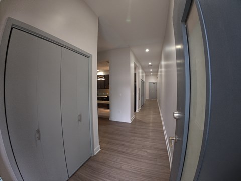 A long hallway with a white door on the left and a grey door on the right.
