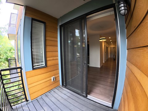 A wooden deck with a glass door leading to a hallway.