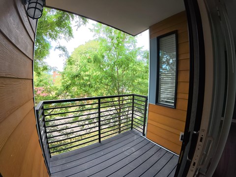 A balcony with a black railing and a view of trees.