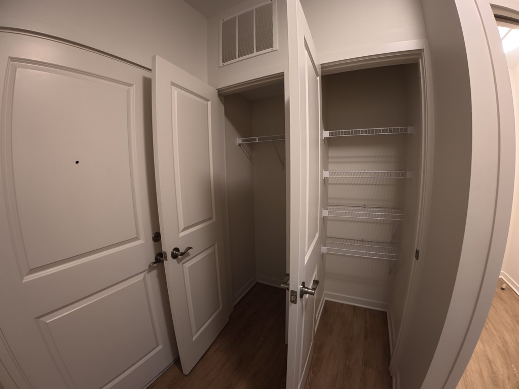 A white pantry with two doors and a shelf.