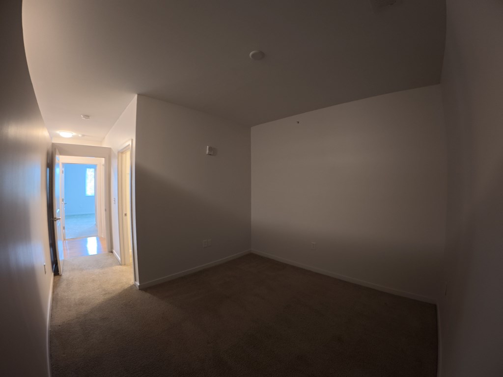 A room with a carpeted floor and a doorway leading to another room.