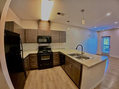 A kitchen with a black refrigerator and a black microwave.