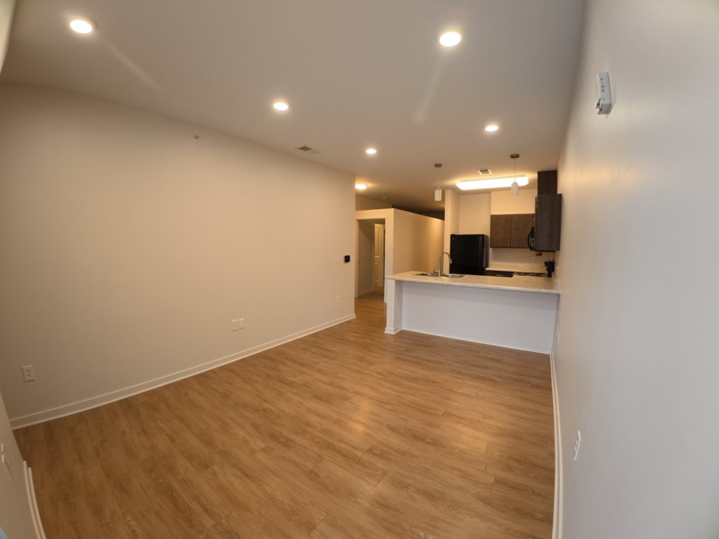 A room with wooden flooring and a white countertop with a black television on it.