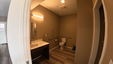 A bathroom with a toilet, sink, and mirror.