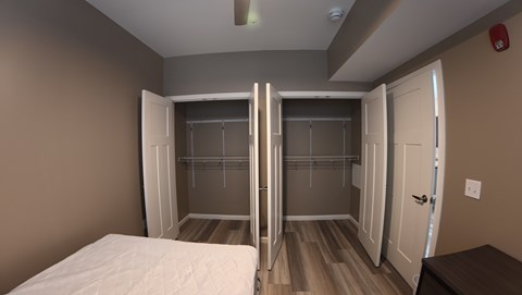 A bedroom with a bed, a wardrobe, and a nightstand.