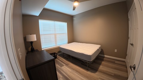 A bedroom with a bed, dresser, and window.