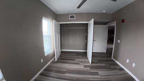 A room with a ceiling fan and a doorway leading to another room.