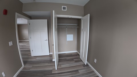 A room with a white door and a white closet with a white shelf.