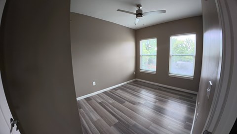 A room with a ceiling fan and wooden flooring.