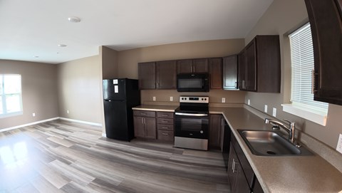 A kitchen with brown cabinets and a black fridge.