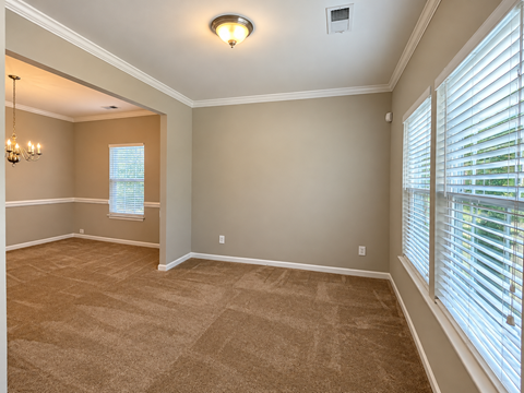 A room with a carpeted floor and a chandelier.