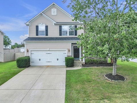 A house with a garage and a tree in front.