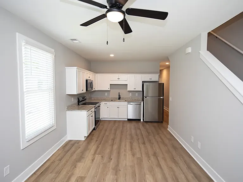A kitchen with white cabinets and a wood floor.