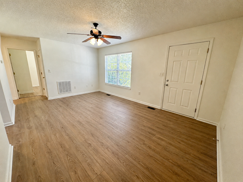 A room with a ceiling fan and wooden flooring.