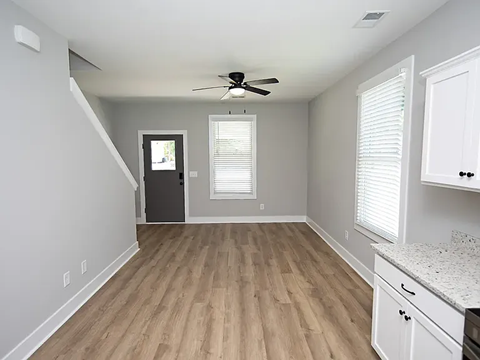 A room with a ceiling fan and a door leading to another room.