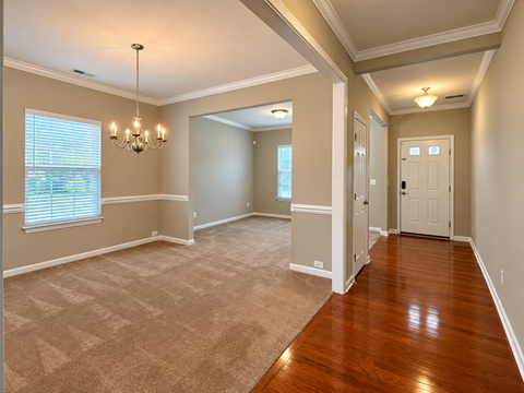 A room with a carpeted floor and wooden flooring in the hallway.