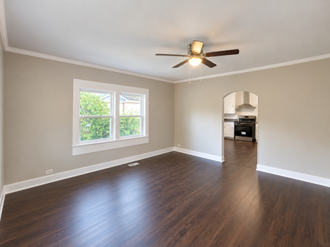 A room with a ceiling fan and wooden flooring.