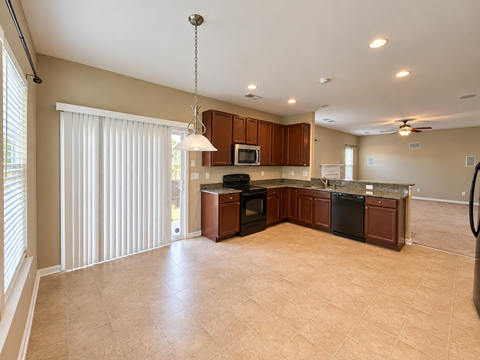 A kitchen with brown cabinets and black appliances.