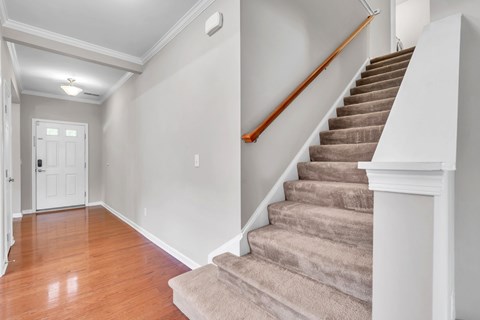 A staircase with a beige carpeted runner and wooden handrail.