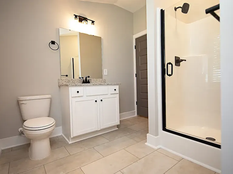 A white toilet sits next to a white cabinet in a bathroom.